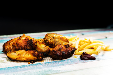 Chicken wings with sauce and golden French fries potatoes