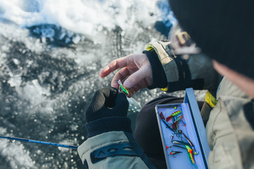 Close up of tackle and equipment for ice fishing in the hands of a professional fisherman. A man...