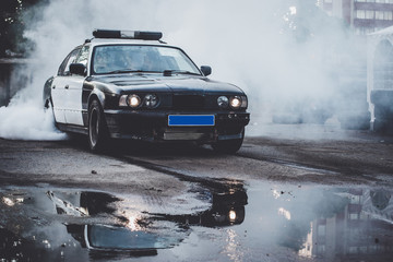 Police car on drift racing motorsport. German driftcar burning tires on asphalt in drift-show. Speed, drive and active sport - obrazy, fototapety, plakaty