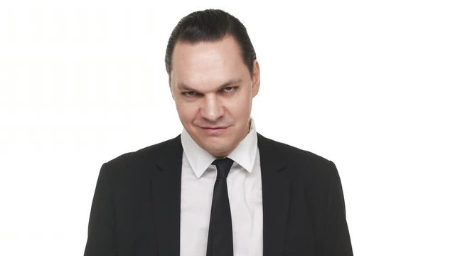 Portrait of self-confident man in classic black suit straightening his tie and looking angrily, over white background in studio. Concept of emotions
