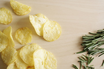 potato chips on a wooden background of rosemary