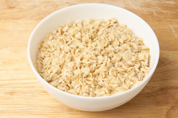 Oatmeal porridge. White bowl. Light background. Healthy food
