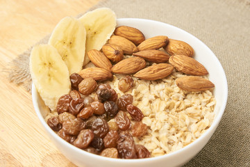 Oatmeal with raisins banana and almonds. Neutral background