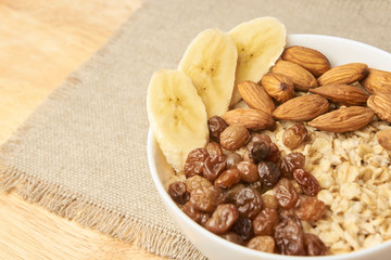 Oatmeal with raisins banana and almonds. Neutral background