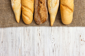 Freshly baked French baguettes on white wooden table. Top view, copy space