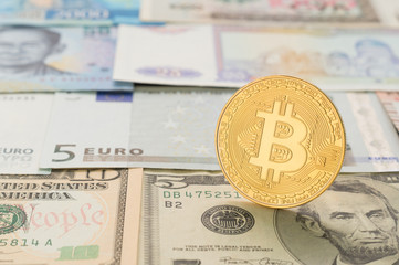 One bitcoin on the background of different banknotes.