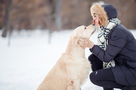 Photo of girl hugging labrador in snowy park