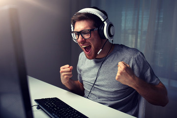 man in headset playing computer video game at home