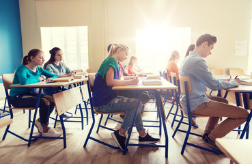 group of students with books writing school test