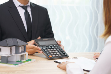 Businessman showing the home price on calculator and customer ready to sign loan contract