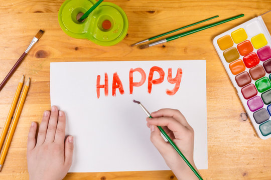 kids hand drawing a greeting card with paintbrush at the table