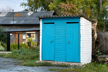Street toilet. Overcast weather. Country buildings. Blue paint