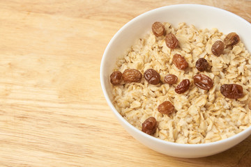 White cup. Delicious healthy breakfast. Oatmeal with raisins