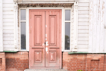 Wooden brown door. Light building wall. Old architecture
