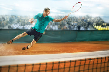 The one jumping player, caucasian fit man, playing tennis on the earthen court with spectators