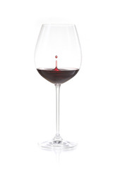 Rotwein in einem Rotweinglas mit einem aufspritzenden Tropfen