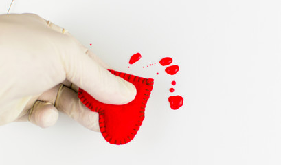The concept of a broken heart. A hand in a rubber glove compresses the heart and blood stains around.