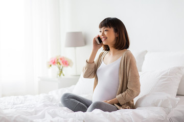 happy pregnant woman calling on smartphone at home