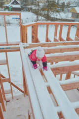 a girl is dangerous to climb on the construction of a frame house in the winter, a brave child