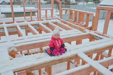 a girl is dangerous to climb on the construction of a frame house in the winter, a brave child