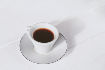 White cup of coffee with amaretti cookies on light white background with copy space.