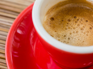 cup of espresso, viewed from above, red cup, straw table, detail