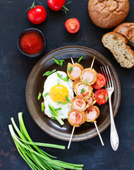 Fried egg with sausages wrapped in pancakes for breakfast.