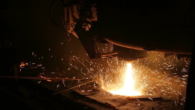 Plant for the production of steel. An electric melting furnace. Factory worker takes a sample for metal.
