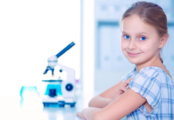 Schoolgirl looking through microscope in science class