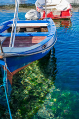 Fototapeta na wymiar View of an old wooden traditional fishing boat floating above clear blue and green transparent sea in the village marina, Croatia