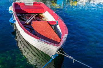 Fototapeta na wymiar View of an old worn out wooden fishing boat floating above clear blue and turquoise mediterranean sea, Croatia