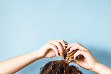 The woman straightens the disheveled bun on her head with her hands with a black manicure. Dark...