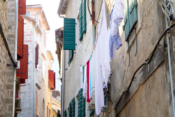 Fototapeta na wymiar Bed sheets drying in the street, windy hot day. Montenegro, Kotor