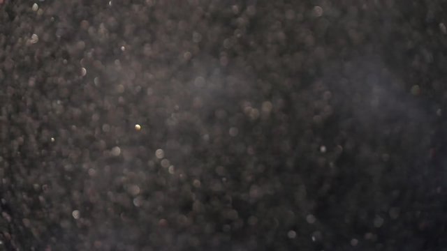 Sunny snowstorm and sparkling defocused snowflakes on dark gray background. Abstract glittering backdrop in slow motion. Excellent meditative and relax intro with blinking gleams.