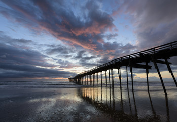 Fishing Pier on Beach with Colorful Sky at Sunrise