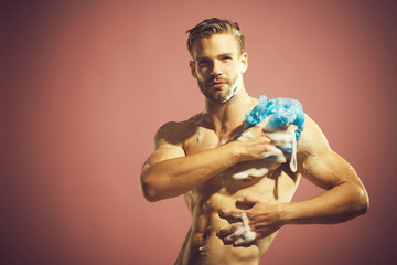 Attractive bearded guy washing in bathroom. Bare man rubbing himself shower gel with sponge....