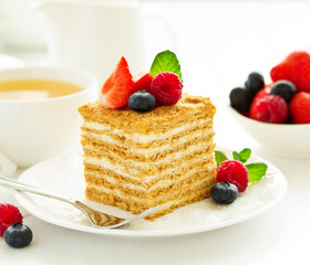 A piece of multi-layered honey cake with fresh berries. Selective focus