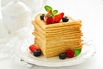 A pile of Russian-style pancakes with berries and honey for the carnival feast...