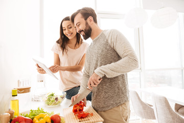 Portrait of a joyful young couple cooking salad