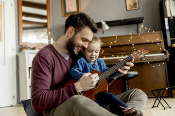 Father teaching daughter to play guitar at home