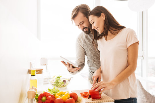 Portrait of a cheerful young couple cooking salad