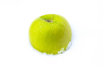 On a white snow is a green apple.