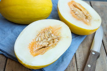 Ripe Organic Fresh Melon Whole and Cut in Half on Blue Napkin Knife on Plank Wood Garden Table. Summer Seasonal Fruits Harvest Vitamins Healthy Diet Concept