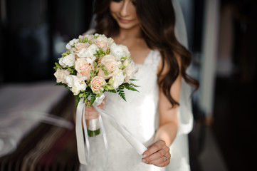 Bride morning preparation. Beautiful bride dressed in a white dress and veil with a wedding bouquet