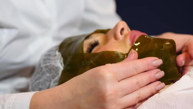algae face mask. Woman on seaweed wrap at a spa salon. Woman is having a procedure in cosmetology cabinet