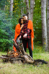 Couple in love at picnic with fire in forest, trees