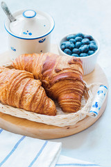Delicious breakfast with fresh croissants and blueberry on light background, bright fresh mood
