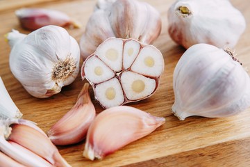 Sliced garlic, garlic cloves and garlic bulbs on wooden background, macro. Spices, culinary, kitchen concept