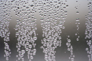 Drops of water on the glass. Gray window background.