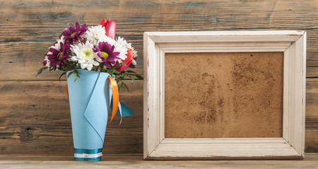 Beautiful bouquet of flower with photo frame on vintage wood background.